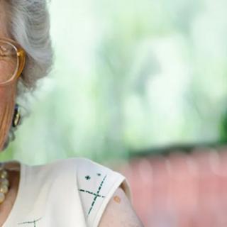 An elderly woman with glasses is outdoors.