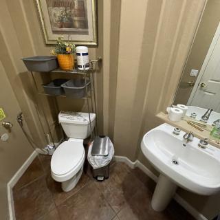 A small bathroom with a toilet, sink, and wall-mounted shelf for storage.
