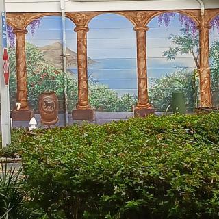 A scenic mural depicting columns overlooking a landscape with greenery in the foreground.