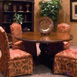 A cozy dining area with a round wooden table and upholstered chairs, accented by a decorative cabinet and potted plant.
