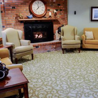 A cozy living room with a brick fireplace, armchairs, and a decorative clock.