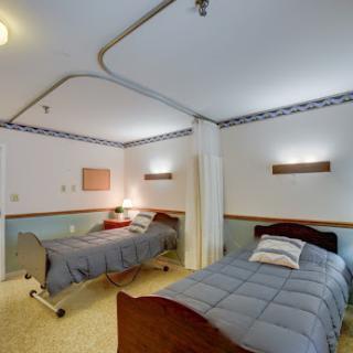 A clean and well-lit hospital room featuring two twin beds, designed for patient comfort.