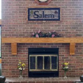 A cozy brick fireplace with a wooden mantel, adorned with flowers and a 'Salem' sign.