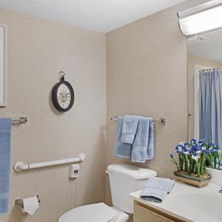 A well-kept bathroom featuring a neatly organized sink area with blue towels and decorative flowers.