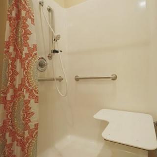 An accessible shower with handrails and a shower seat.