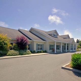 A single-story building with a sloped roof surrounded by greenery under a clear blue sky.
