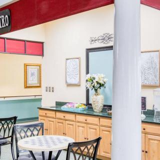 A cozy lobby reception area with tables and chairs, decorated with flowers and artwork.