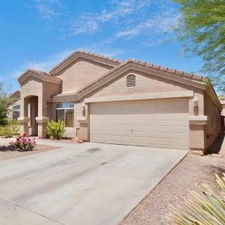 A suburban single-story house with a two-car garage and desert landscaping in front.