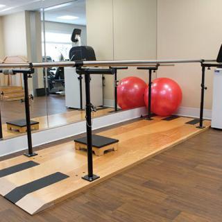 An exercise studio featuring a ballet barre, mirrors, and fitness equipment.