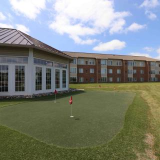 A putting green beside a building under a partly cloudy sky.