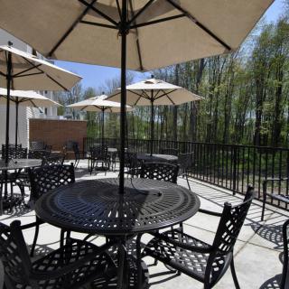 A sunny outdoor patio area with tables, chairs, and umbrellas.