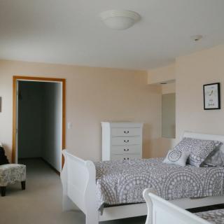 A cozy bedroom with a white bed, dresser, and patterned bedspread.