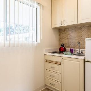 A compact apartment kitchen with light-colored cabinets and a small window.