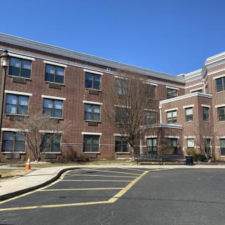 A brick school building with multiple windows under a clear blue sky.