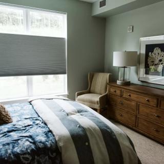 A cozy bedroom with a bed, dresser, and artwork.