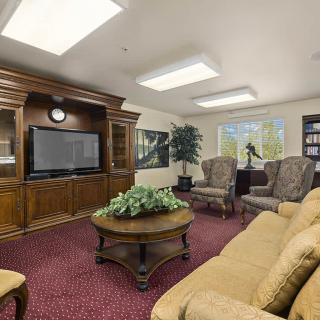 A cozy living room with plush seating, a large television, and elegant wooden furniture.