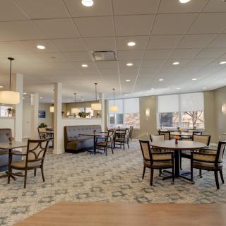A modern dining area with tables and chairs, illuminated by overhead lighting.