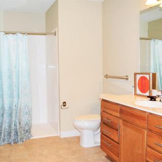A clean and spacious bathroom with a shower, toilet, and wooden cabinets.