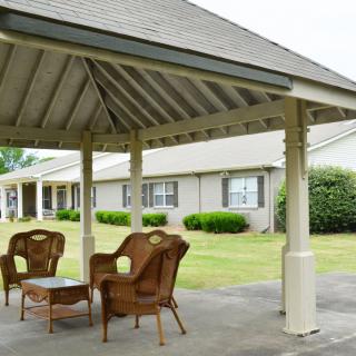 A cozy outdoor gazebo with wicker furniture on a lawn.