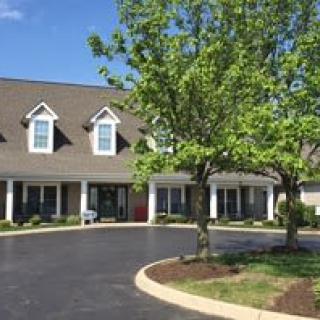 A suburban residential building with a driveway and surrounding trees.