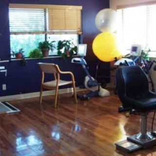 A well-lit exercise room with fitness equipment and plants.
