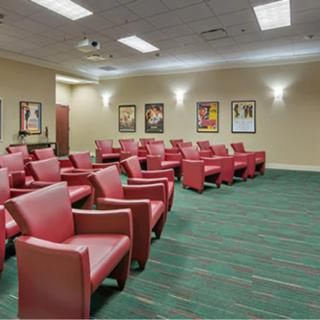 An empty auditorium with red chairs arranged in rows and posters on the walls.