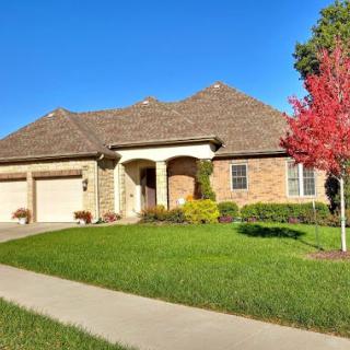 A beautiful brick home with a well-maintained lawn and vibrant fall colors.