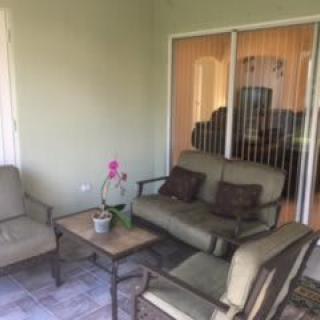 A cozy patio with comfortable seating and a small table adorned with an orchid.