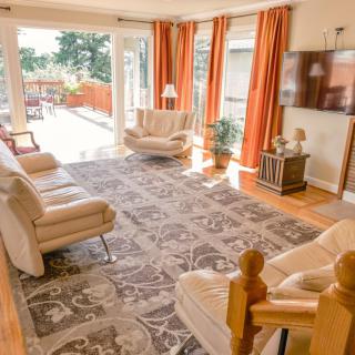 A spacious and bright living room with comfortable seating, a large rug, and floor-to-ceiling windows letting in plenty of natural light.