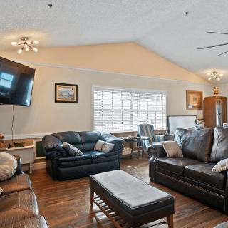 A cozy living room with leather sofas, a mounted television, and wooden floors.