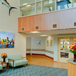 A welcoming hospital lobby featuring comfortable seating, colorful flower arrangements, and modern artwork.