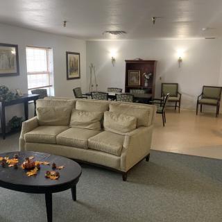 A cozy living room with a beige sofa, coffee table, and chairs, featuring elegant decor and ample natural light.