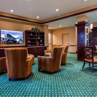 A well-furnished lobby area with striped armchairs, a television, and a bookshelf on a patterned carpet.