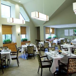 A spacious and elegantly designed dining area with well-set tables, modern lighting, and a warm ambiance.