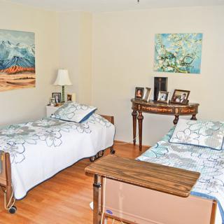 A cozy bedroom with two neatly made beds, adorned with paintings and family photographs.