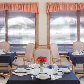 A cozy dining room with elegantly set tables and flower centerpieces.