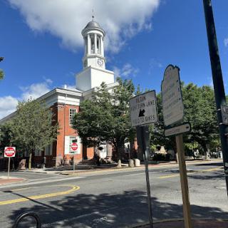 A view of a prominent building with a clock tower against a blue sky dotted with clouds.