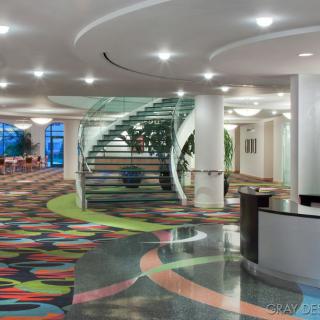 A modern lobby featuring a colorful carpet and a sleek spiral staircase.