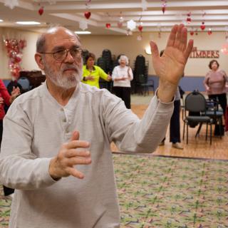 A group of senior citizens practicing Tai Chi indoors for health and wellness.
