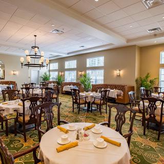 An elegant dining room with neatly arranged tables and chairs, featuring sophisticated lighting.
