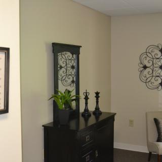 A stylishly decorated corner of a room featuring a dresser with a mirror, decorative items, and wall art.