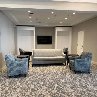 A modern lounge area featuring a grey sofa and blue armchairs, set on a patterned carpet.