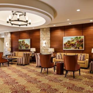A cozy hotel lobby featuring comfortable seating, warm lighting, and elegant artwork on the walls.