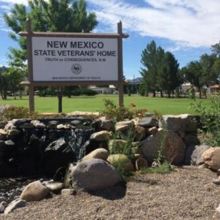 Entrance sign of the New Mexico State Veterans Home surrounded by greenery and a landscaped garden.