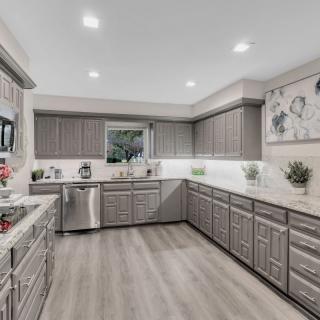 A modern kitchen with gray cabinets and stainless steel appliances, featuring a spacious layout and recessed lighting.