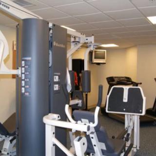 A gym with various exercise equipment, including a treadmill and strength training machines.