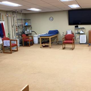 A spacious physical therapy room with exercise equipment and seating areas.