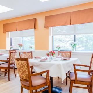 A bright and inviting dining room with elegantly set tables and comfortable chairs.