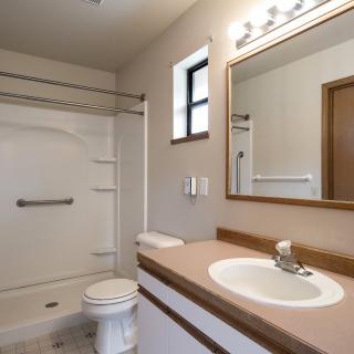 A clean and modern bathroom with a shower, toilet, sink, and large mirror.