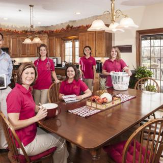 A group of people in a kitchen, possibly preparing or cleaning.